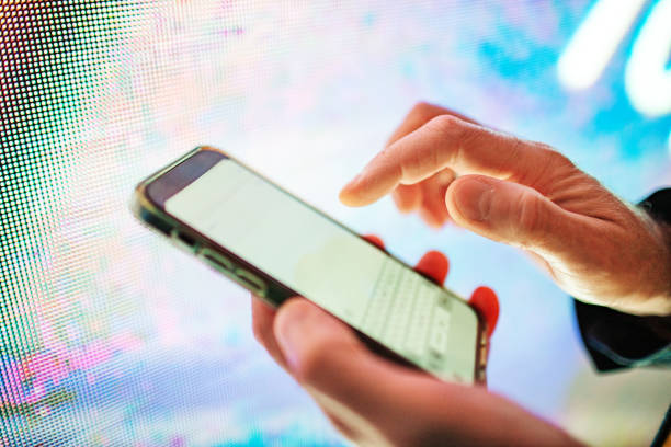 istock Closeup of mobile in hands with neon light billboard at background 2184036277