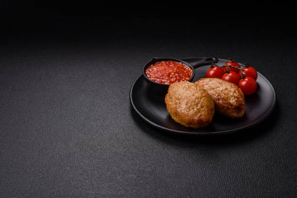 Delicious fresh fried minced fish cutlets with spices and herbs on a dark concrete background