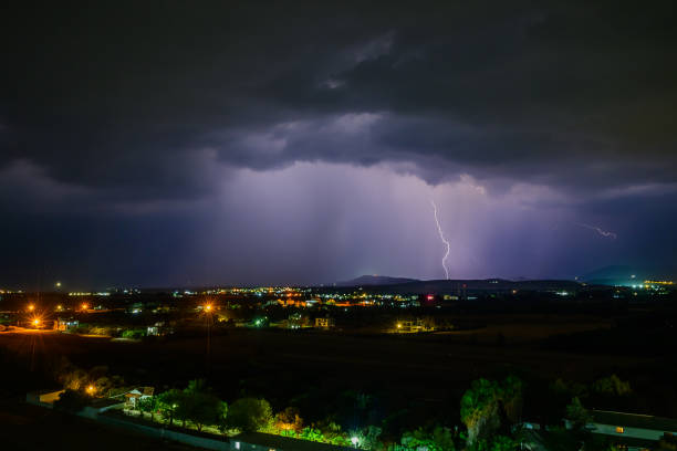 istock A stunning thunderstorm lights up the night sky over a serene rural landscape. 2184052047