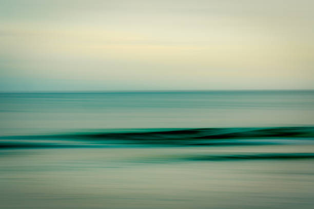 Abstract motion blur of ocean waves and sky in soft, muted tones.