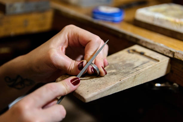 Jeweler carefully working on a metal ring, smoothing and polishing it with a file, demonstrating craftsmanship and precision
