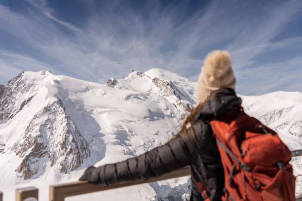 istock Mountain woman with red backpack looking at snowy mountain 2184057679