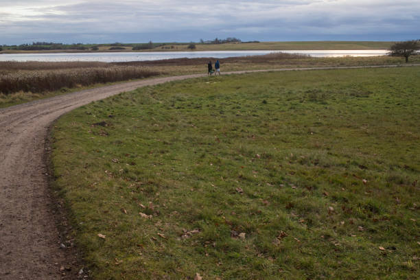A view of a path leading to a lake in the countryside, with a couple walking by