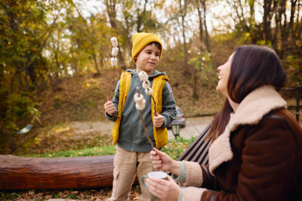 istock Mother and Son Enjoying Marshmallow Roast in Autumn Forest 2184060817