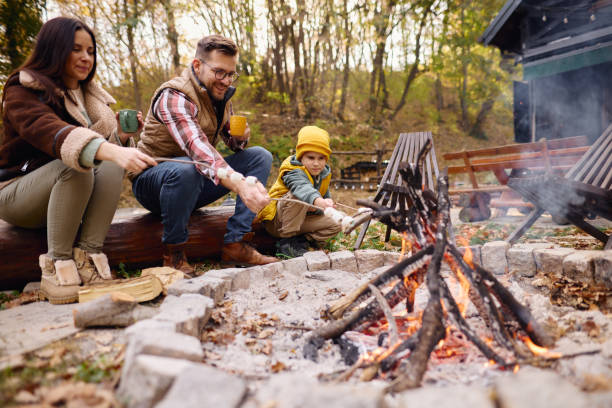 istock Family Enjoying Campfire in Autumn Forest Roasting Marshmallows 2184061147