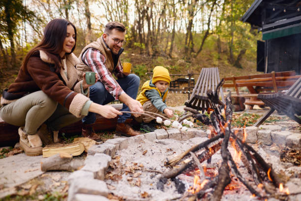 istock Family Enjoying Campfire in Autumn Forest Roasting Marshmallows 2184061153