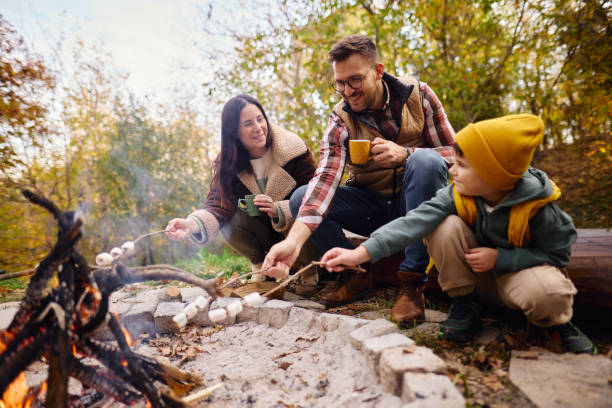 istock Family Enjoying Campfire in Autumn Forest Roasting Marshmallows 2184061163