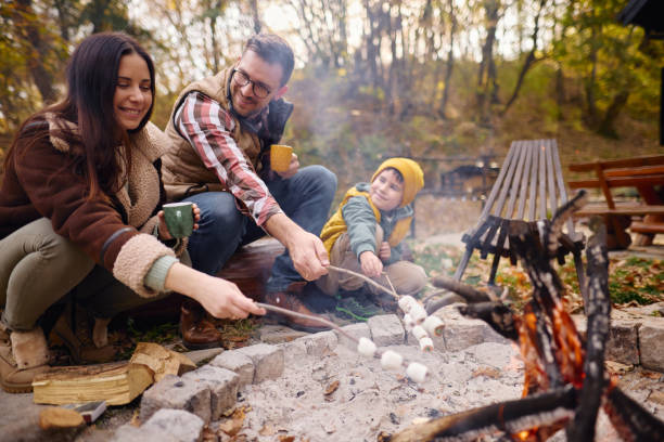 istock Family Enjoying Campfire in Autumn Forest Roasting Marshmallows 2184061170