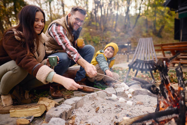 istock Family Enjoying Campfire in Autumn Forest Roasting Marshmallows 2184061172