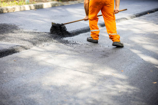 istock Construction worker repairing asphalt road during daytime, using a lute rake to spread fresh material in an urban environment 2184061181