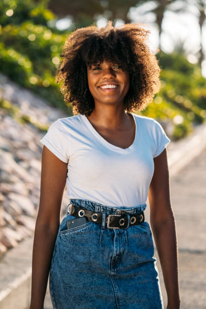 istock Young black woman smiling and walking outdoors on a sunny day 2184068784