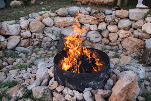 A cozy campfire radiates warmth and relaxation, surrounded by a rustic circle of stones. Perfect for gathering with family and friends on a summer evening outdoors.