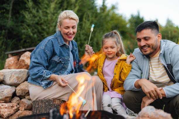 Family Enjoying Campfire While Roasting Marshmallows Outdoors In Nature