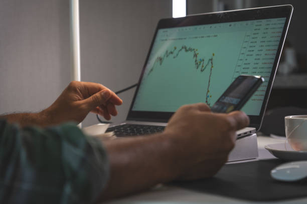 istock A man is using a laptop and a cell phone to look at stock market data 2184072391