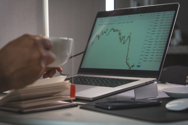 istock A person is holding a cup of coffee while looking at a laptop screen 2184072392