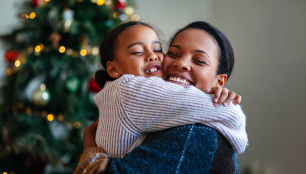 istock Joyful Mother and Daughter Hugging by Christmas Tree 2184072626