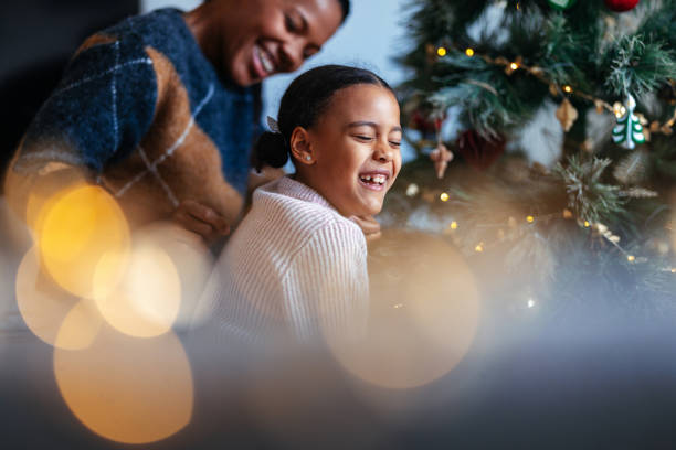 Mother and Daughter Laughing by Festive Christmas Tree