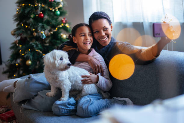 istock Mother and Daughter Taking a Holiday Selfie by Christmas Tree 2184072700