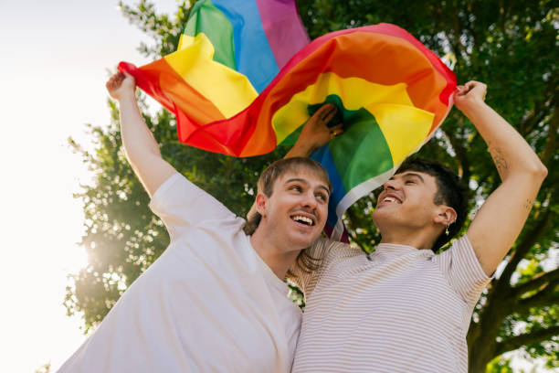 istock Two men holding rainbow flag celebrating lgbtq+ pride in a park 2184073099