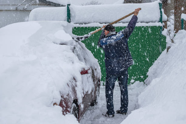 istock A man is shoveling snow off a red car 2184073782