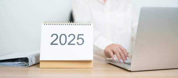 istock 2025 Year Calendar on table with business woman using laptop computer, working and writing in office. countdown, Happy New Year, Resolution, Year End and New Start and Goals Plan Action Concept 2184082678