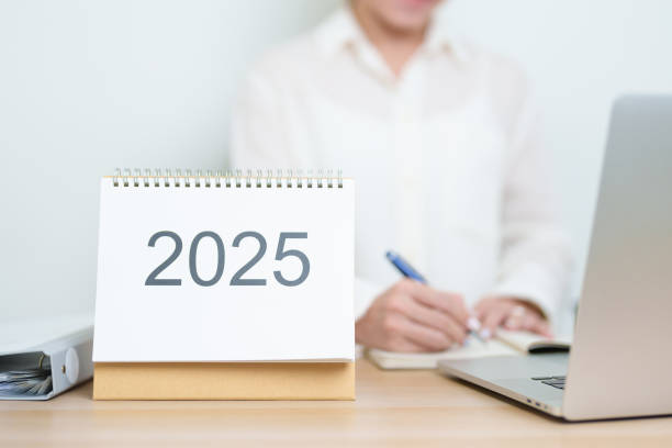 istock 2025 Year Calendar on table with business woman using laptop computer, working and writing in office. countdown, Happy New Year, Resolution, Year End and New Start and Goals Plan Action Concept 2184082679