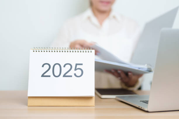 istock 2025 Year Calendar on table with business woman using laptop computer, working and writing in office. countdown, Happy New Year, Resolution, Year End and New Start and Goals Plan Action Concept 2184082680