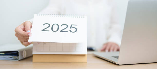 istock 2025 Year Calendar on table with business woman using laptop computer, working and writing in office. countdown, Happy New Year, Resolution, Year End and New Start and Goals Plan Action Concept 2184082706