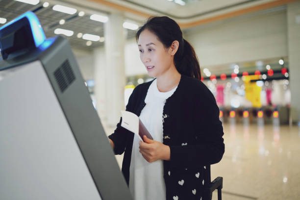 istock A Woman Using a Self-Service Kiosk at the Airport for Check-In 2184087529