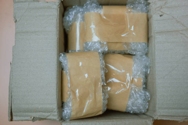 istock Packing fragile items with plastic air bubble wrapped and adhesive tape in box. 2184088597