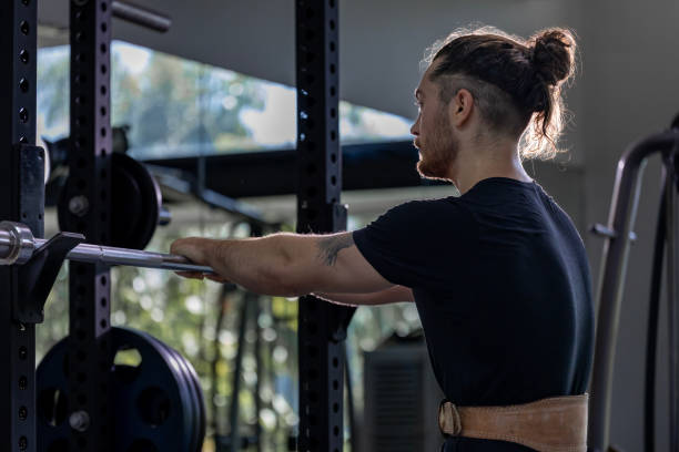 istock Caucasian muscular body builder sport man is practice weight training on squat barbell for core muscle inside gym with dark background for exercising and workout 2184088726