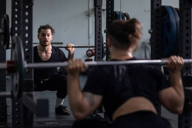 istock Caucasian muscular body builder sport man is practice weight training on squat barbell for core muscle inside gym with dark background for exercising and workout 2184088727