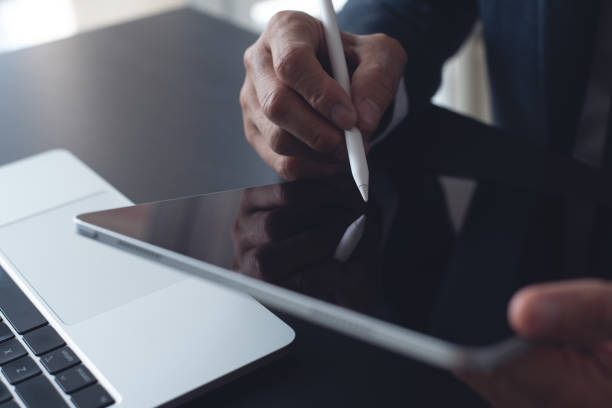 istock Close up, businessman using stylus pen signing e-document on digital tablet at office, E-signing, electronic signature concept. Business man online working on computer devices on office desk 2184097247