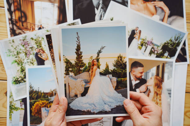 istock Men's hands put on the table and show wedding photos. 2184097457