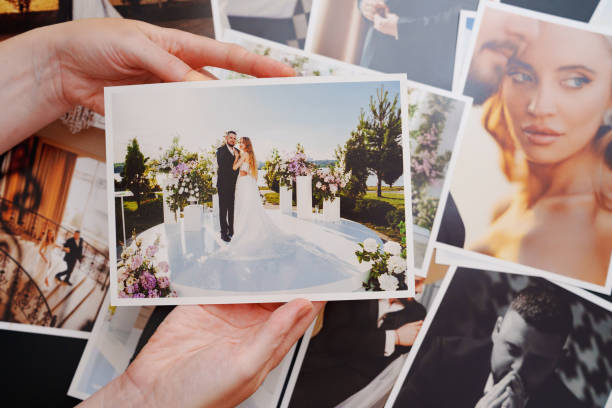 istock women's hands put on the table and show wedding photos. 2184099704