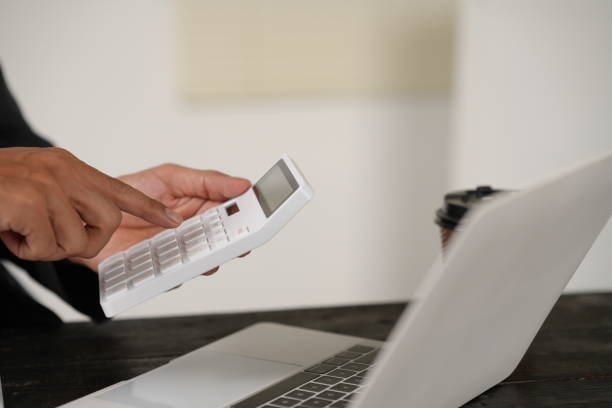istock A focused businessman sits at his office desk, analyzing a paper chart while working on his laptop. He examines financial and marketing reports, concentrating on data for strategic decision-making. 2184099847