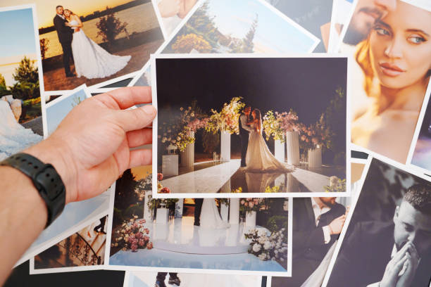 istock Men's hands put on the table and show wedding photos. 2184099876
