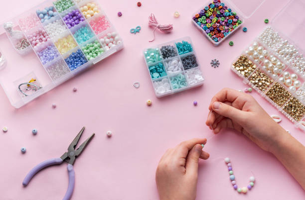 istock Creating colorful beaded jewelry with assorted beads and crafting tools on a light pink surface 2184099889