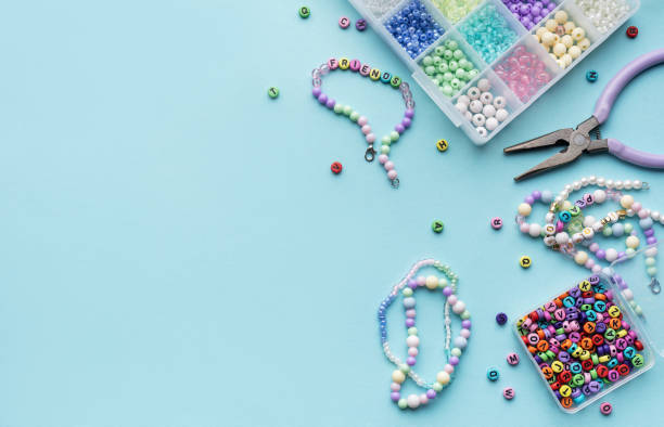istock Colorful assortment of beads and jewelry-making tools on a blue surface with completed bracelets 2184099894