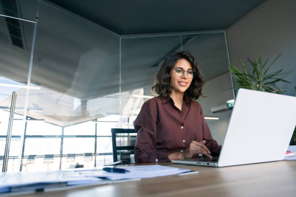 istock Young businesswoman professional employee using pc doing online banking analysing at workplace. Latin hispanic middle age business woman working on laptop computer in modern office. Banner, copy space 2184105579
