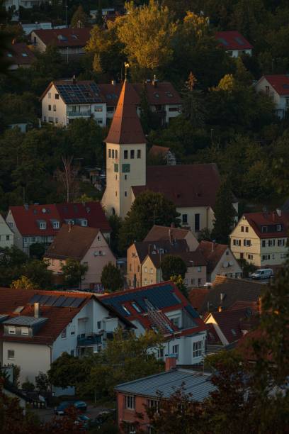 Stuttgart, Germany – September 06, 2024: An evening cityscape of Botnang, a Stuttgart suburb, with warmly lit homes nestled among rolling hills and lush greenery