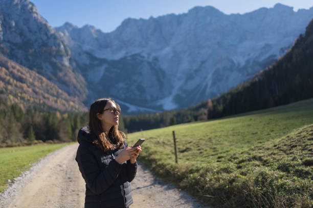 istock Young woman uses phone on road in mountains 2184110281