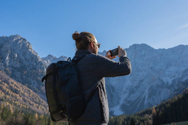 istock Young man takes photo on road in mountains 2184110363