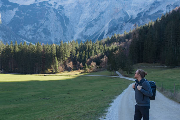 Young man walks down road in mountains, Zgornje Jezersko