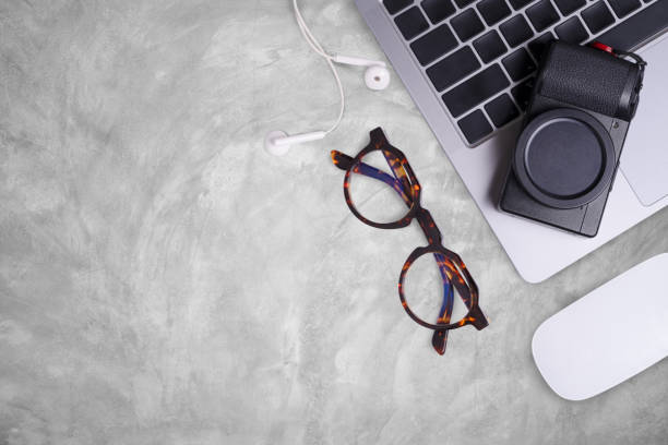istock Flat lay gray concrete table office desk top with computer and camera, eye glasses, mouse and supplies. 2184110487