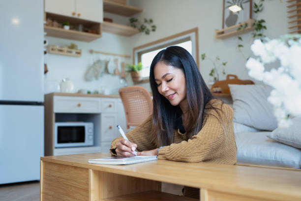 istock Attractive young woman taking notes with a smile in minimalist room 2184113944
