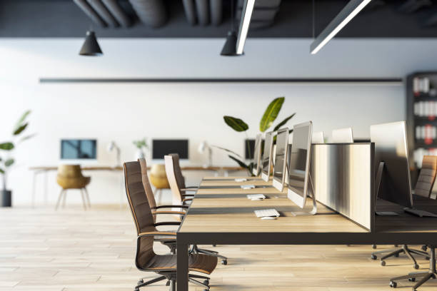 istock Modern office interior with wooden desks, ergonomic chairs, computers, and plants. Bright workspace with a loft design. 3D Rendering 2184114456