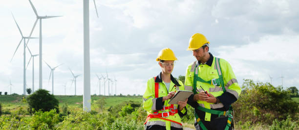 istock Two workers in safety gear are looking at a tablet while standing in a field 2184114906