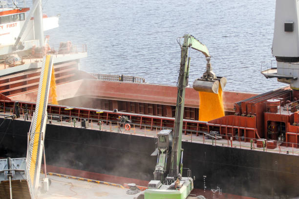 istock Loading of corn into the ships hold at the same time by a mobile conveyor and a grab manipulator 2184114917