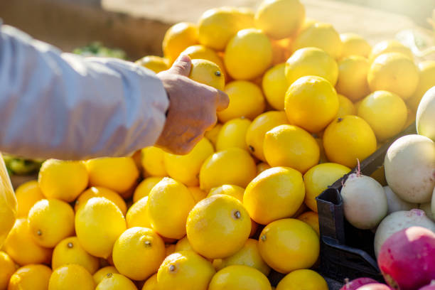 istock Man's hand selecting lemons at local market 2184114942